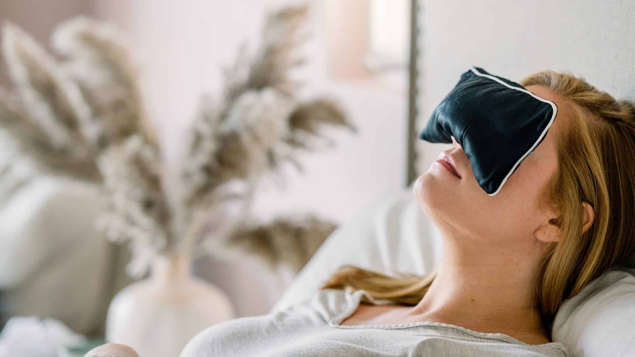 woman laying down with a sleep mask - benefits of sleeping with crystals under your pillow