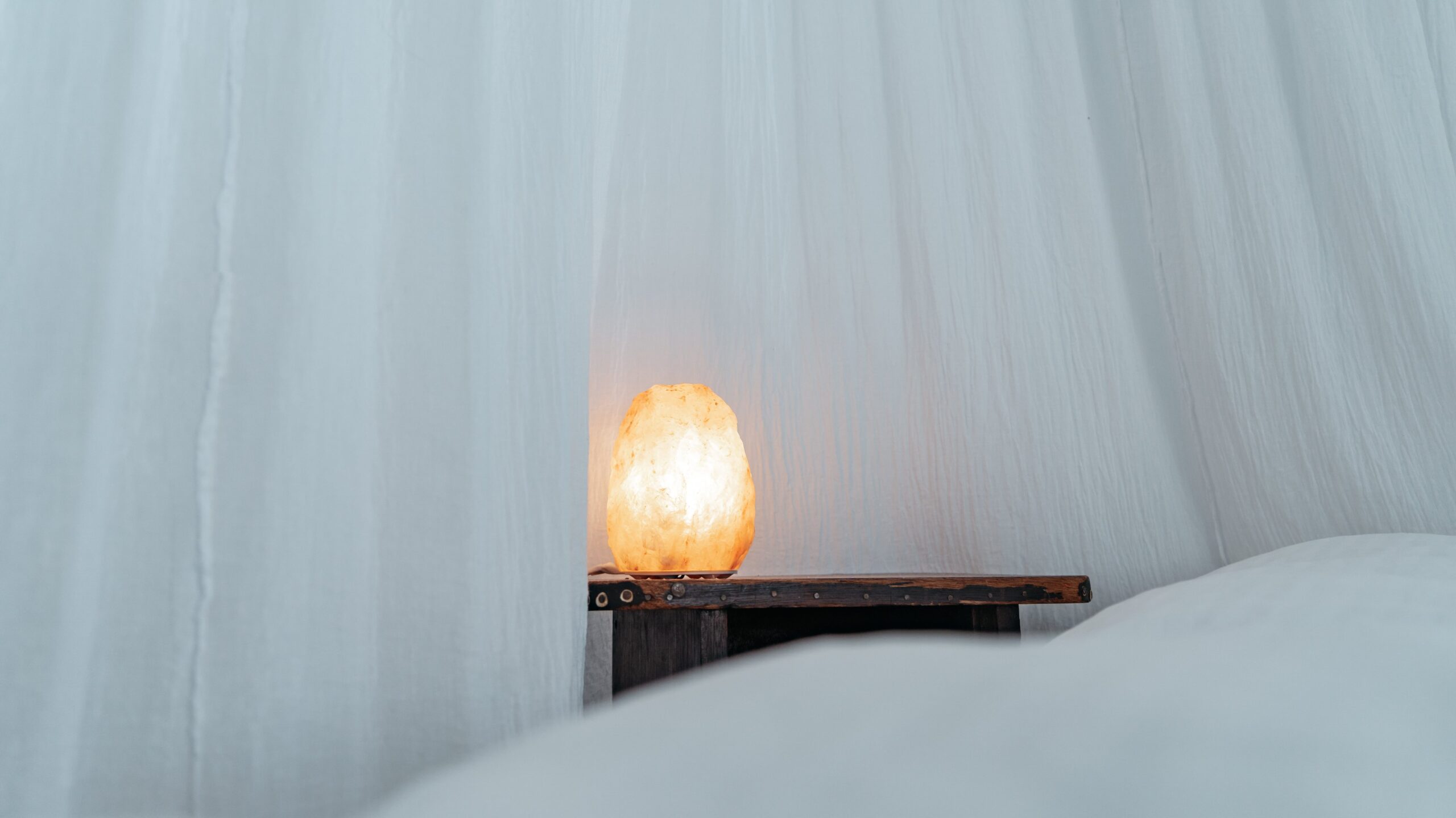 Himalayan salt lamp in a white room - benefits of sleeping with crystals under your pillow